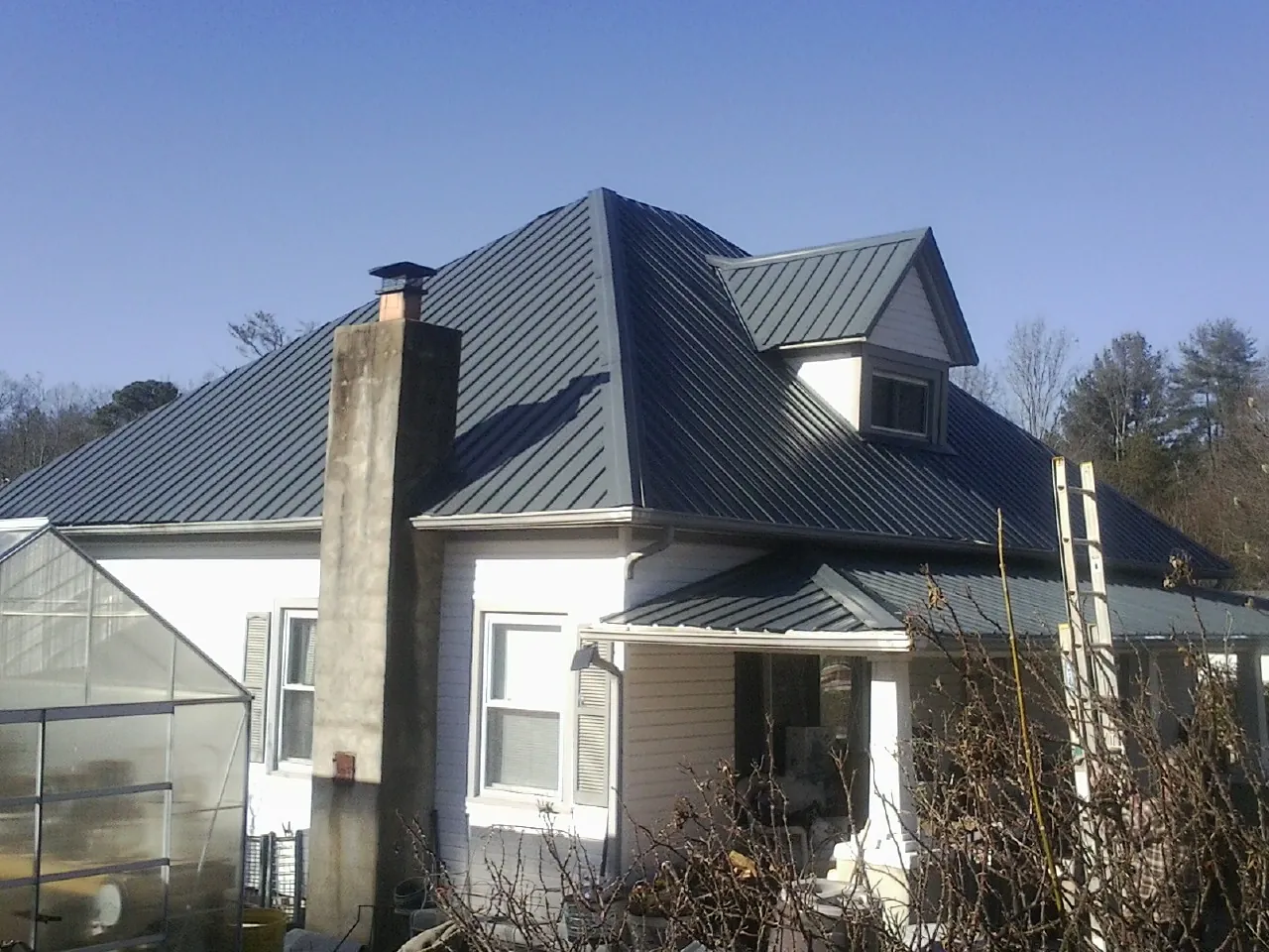 Dark blue standing seam metal roof on a white farmhouse with dormer — Slate & Tile Roof Repair by Roofing Brothers in East Pittsburgh