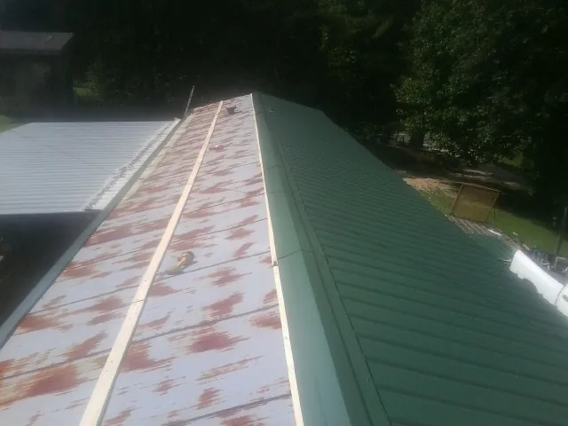 Old rusted panels beside newly installed green metal roofing — Wind Damage Roof Repair by Roofing Brothers in East Pittsburgh