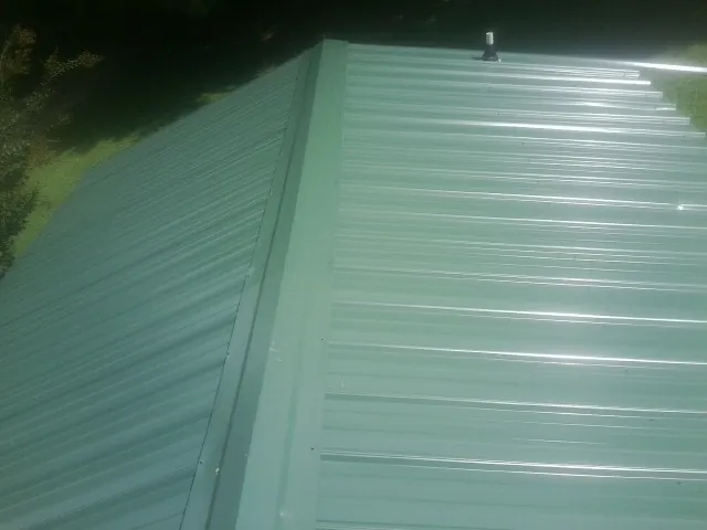 New green metal panels meeting at the ridge of a roof — Flat Roof Repair work by our crew in East Pittsburgh
