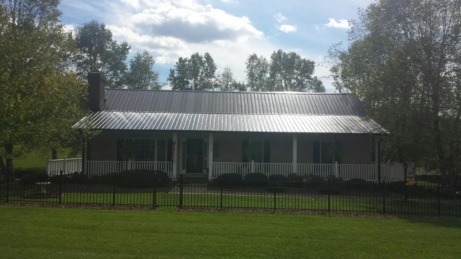 Gray metal roof on a brick ranch with a full width front porch — Gutter Guard Installation work by our crew in East Pittsburgh