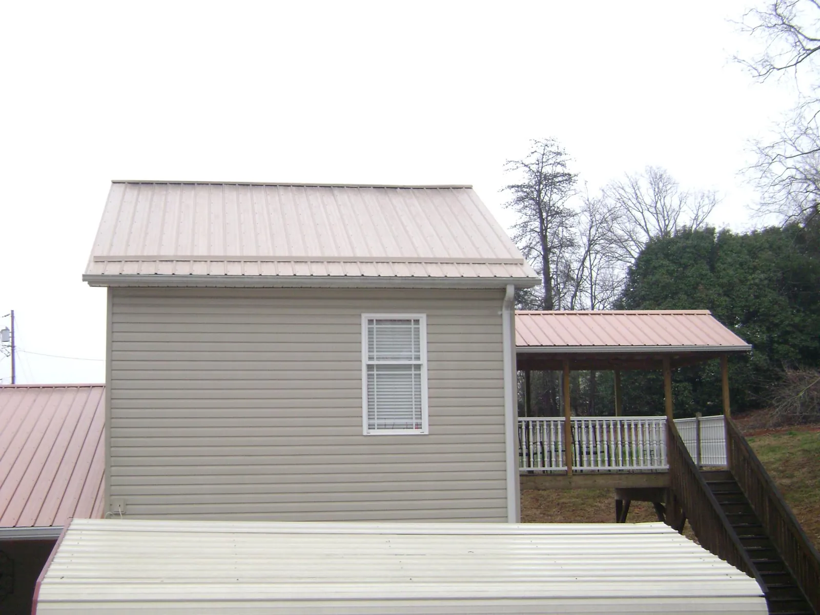 Tan metal roofs on a two story addition and attached porch, from a Roof Replacement job in East Pittsburgh