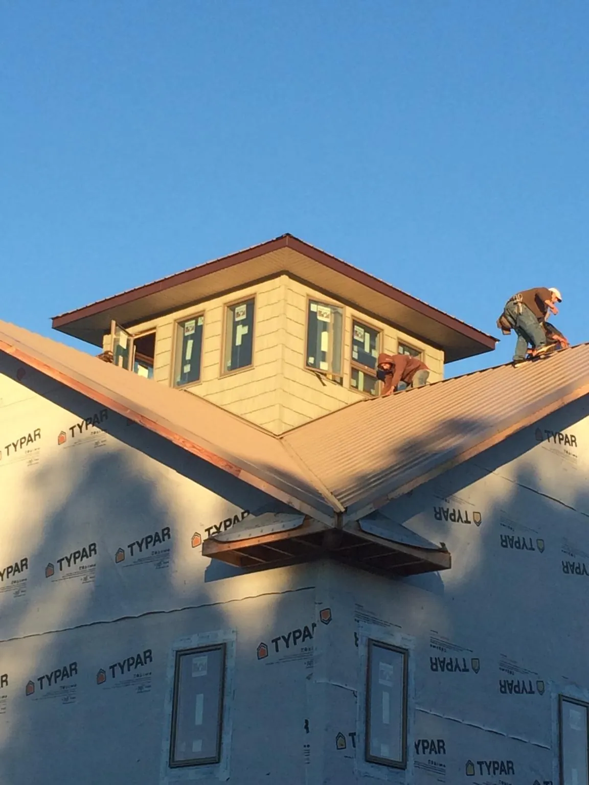 Roofers working around a rooftop cupola on a new metal roof at sunset — Roof Waterproofing in East Pittsburgh by Roofing Brothers